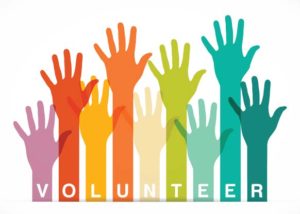 Rainbow colored arms and hands of different lengths being raised and the word volunteer beneath the raised hands