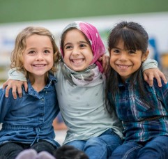 three smiling children with arms around each other, from Help Me Grow website