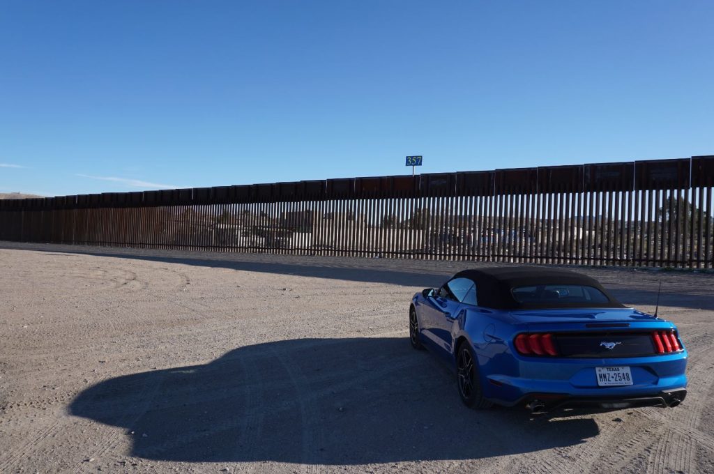 Car w/ texas license plates parked in front of us mexico border wall