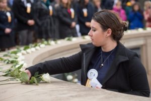 Picture of a past Remembrance scholar laying a rose on the Remembrance wall