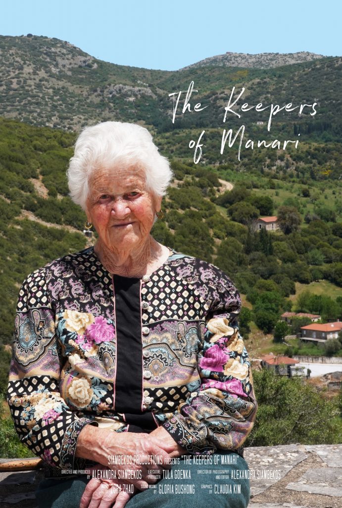 Photo of a Greek elderly woman sitting on a stone wall with a mountainous background.